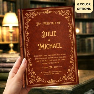 Könnte beinhalten: Eine dunkelbraune buchartige Hochzeitseinladung mit goldener Schrift und floralen Verzierungen. Der Text lautet: The Fairytale of Julie & Michael, Once upon a time, two hearts fell in love, June 24 2029, The Library Ballroom, London.