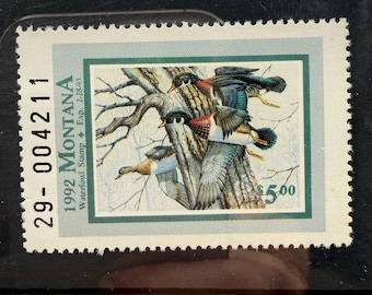 May include: A 1992 Montana Waterfowl Stamp featuring a detailed illustration of three wood ducks perched on a tree branch. The stamp includes the text 29-004211, 1992 MONTANA, Waterfowl Stamp, Exp. 2-28-93, and a $5.00 denomination in green ink.