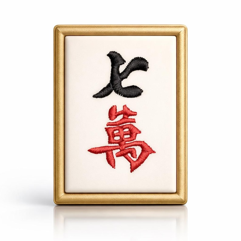 May include: A rectangular Mahjong tile with a gold frame. The tile features black and red embroidered Chinese characters on a white background. The characters are stylized and intricate, with a glossy finish.