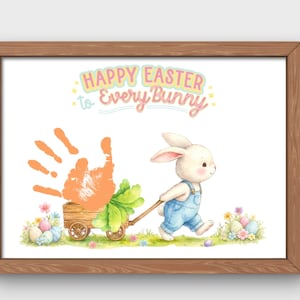 May include: A framed print with a watercolor illustration for Easter. A white bunny in blue overalls pulls a wooden cart with a carrot and handprint. The text reads "Happy Easter to Every Bunny" in pastel colors. Easter eggs and flowers are also depicted.