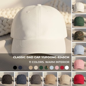 Peut inclure: Casquette de baseball blanche classique avec une visière incurvée. L'image présente une variété de couleurs disponibles, dont le noir, le bleu marine et le rose. Le texte indique "CLASSIC DAD CAP YUPOONG 6245CM 11 COULEURS. INTÉRIEUR CHAUD."