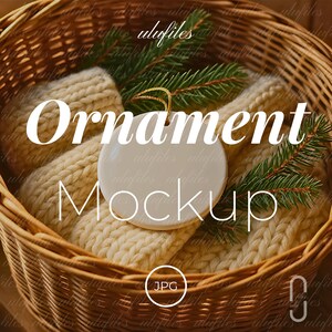 Puede incluir: Una maqueta de adorno de cerámica blanca con el texto "Ornament Mockup" se muestra en una cesta tejida con artículos de punto color crema y ramitas de hoja perenne. La imagen tiene una estética cálida y acogedora, perfecta para presentaciones de productos navideños.
