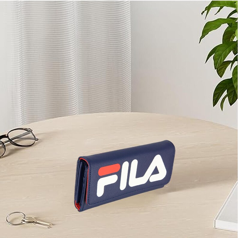Pu&ograve; includere: Un portafoglio blu navy con il logo "FILA" bianco e rosso. Il portafoglio &egrave; rettangolare e sembra essere in pelle o un materiale simile. L'interno &egrave; rosso. Il portafoglio &egrave; su un tavolo marrone chiaro.