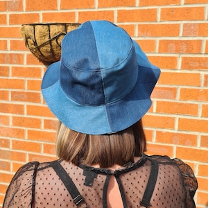 May include: A blue denim bucket hat with a contrasting denim panel. The hat is made of two different shades of blue denim.