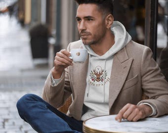Może przedstawiać: Biała bluza z kapturem z grafiką jelenia i tekstem "Worth Fit A Pint". Model nosi bluzę z brązową kurtką i niebieskimi dżinsami.