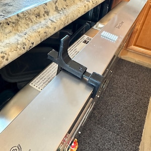 May include: A black 3D-printed dishwasher door lock installed on a stainless steel dishwasher. The dishwasher door is partially open, revealing the interior. The text "Direct Drive" is visible on the door. The appliance has the "Smart Diagnosis" logo.