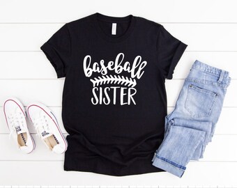 May include: Black t-shirt with white text that says "baseball sister" with a baseball stitch design.