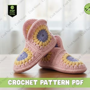 May include: A pair of pink crocheted slippers with sunflower designs in yellow and purple. The slippers are handmade and feature the text "CROCHET PATTERN PDF". The slippers are on a wooden surface.