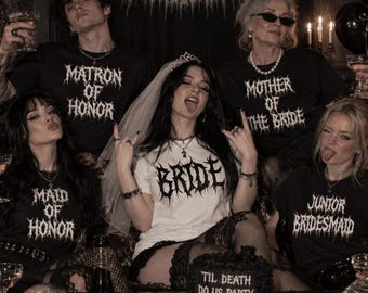 May include: A group of five people wearing black and white t-shirts with metal-style font text including Matron of Honor, Mother of the Bride, Maid of Honor, Bride, and Junior Bridesmaid. The bride wears a veil and a cake reads Til Death Do Us Party.