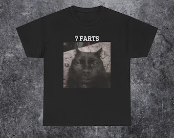 May include: A black short-sleeved t-shirt featuring a centered square graphic of a black cat with a serious expression. Above the cat image, the text 7 FARTS is printed in a white, bold, sans-serif font. The shirt has a crew neckline and short sleeves.
