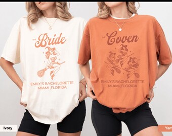 May include: An ivory t-shirt with a graphic of a witch on a broomstick and the text "The Bride EMILY'S BACHELORETTE MIAMI, FLORIDA" and an orange t-shirt with three witches on broomsticks and the text "The Coven EMILY'S BACHELORETTE MIAMI, FLORIDA".