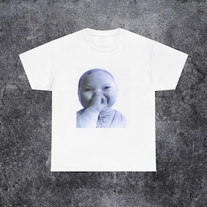 May include: White t-shirt featuring a blue-toned image of a baby with a finger in its nose. The baby is smiling. The t-shirt is made of a soft, comfortable material.