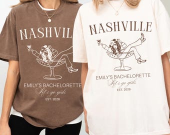 May include: Two crewneck t-shirts, one brown and one cream, featuring a graphic of a person in a cowboy hat inside a martini glass. Text reads: NASHVILLE, EMILY'S BACHELORETTE, Let's go girls, and EST. 2026. The design is printed in a contrasting color.