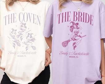 May include: Two t-shirts featuring graphic prints. The cream shirt displays three pin-up witches on broomsticks with the text THE COVEN, Emily's Bachelorette, and MIAMI, FL. The lavender shirt shows one witch with THE BRIDE, Emily's Bachelorette, and MIAMI, FL.