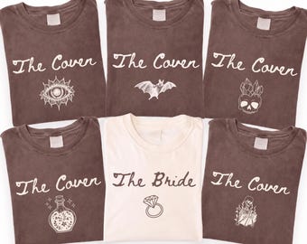 May include: Five brown t-shirts and one white t-shirt. The brown shirts feature the text The Coven with graphics of an eye, a bat, a crystal skull, a potion bottle, and a skeleton. The white shirt features the text The Bride with a ring graphic.