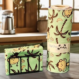 May include: A set of green kitchen towels and napkins with a playful monkey and palm tree pattern. The napkins are in a black metal holder. A roll of matching towels is also visible, with the text "Playful Panda".