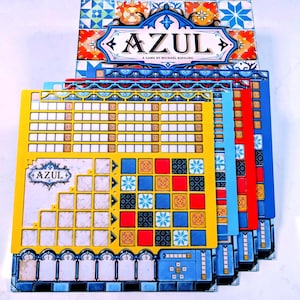以下が含まれることがあります： ボードゲームAzulが表示されています。ゲームタイトルが書かれた箱と、プレイヤーボードが重ねられています。ボードは黄色、青、赤、水色で、タイルとスコアリング用のスペースがあります。ゲームボックスには、ゲームタイトルが書かれた装飾的なデザインが施されています。