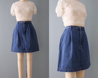 Könnte beinhalten: Ein blauer Jeans-Minirock mit hoher Taille und geradem Schnitt. Der Rock hat einen Reißverschluss und einen Knopfverschluss vorne.