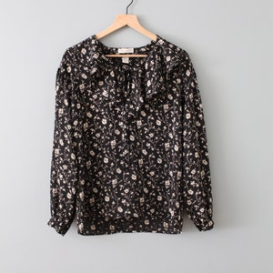 May include: A black long-sleeved blouse with a white floral print and a large ruffled collar.
