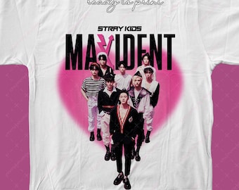 Op de afbeelding: Een wit T-shirt met een roze hartontwerp met de tekst "Stray Kids" en "Maxident" in zwart. De afbeelding toont een groep van zeven mannen in zwart-witte kleding die in het hart staan.