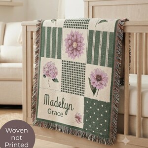 Könnte beinhalten: Eine gewebte Wohndecke mit einem Patchwork-Design aus cremefarbenen und dunkelgrünen Quadraten mit Streifen, Punkten und Karomustern. Die Decke zeigt rosa Blumenillustrationen und den personalisierten Text Madelyn Grace.