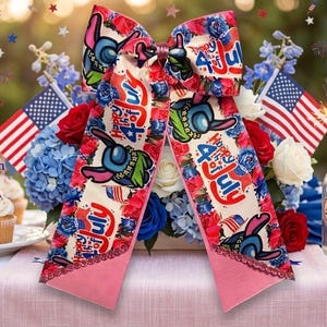 Può includere: Un grande fiocco decorativo a tema patriottico. Il fiocco presenta un centro color crema con un personaggio dei cartoni animati, la scritta "Happy 4th of July" e accenti floreali rossi, bianchi e blu. Le code del fiocco sono rosa con un bordo in pizzo.