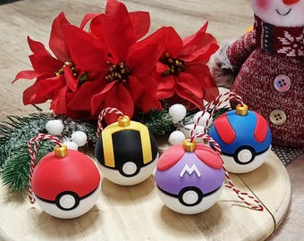 May include: A collection of colorful Christmas ornaments with a Pokémon theme. The ornaments are red, black, blue, and purple with white and gold accents. Each ornament has a unique design and a red and white string for hanging.