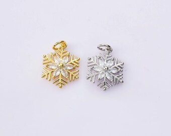 Könnte beinhalten: Zwei Schneeflocken-Anhänger, einer goldfarben und einer silberfarben, jeweils mit einem zentralen Blumendesign. Der goldfarbene Anhänger hat ein glänzendes Finish, während der silberfarbene Anhänger einen polierten Look hat. Beide haben eine kleine Schlaufe.