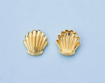 Può includere: Due orecchini dorati a forma di conchiglia su sfondo azzurro. Gli orecchini hanno un design dettagliato e scanalato, con una superficie lucida e riflettente. Gli orecchini sono a tema nautico classico.