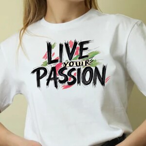 Può includere: T-shirt bianco con la scritta "LIVE YOUR PASSION" in nero, con lettering a pennellate. Il testo è impreziosito da pennellate verdi e rosse. La maglietta è in stile girocollo.