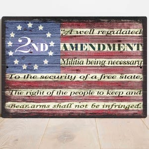 May include: A wooden sign with a distressed American flag design. The sign features the text "2ND AMENDMENT" and the full text of the Second Amendment to the United States Constitution.