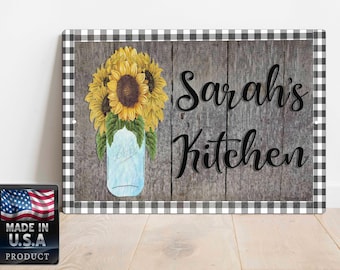 Può includere: Un cartello a scacchi bianco e nero con uno sfondo in legno. Il cartello presenta un barattolo di vetro pieno di girasoli e il testo "Sarah's Kitchen".