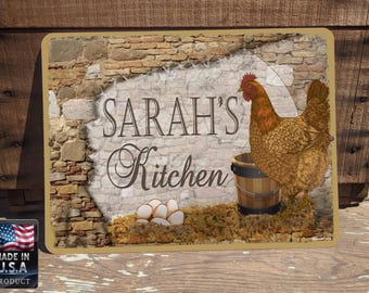 Peut inclure: Une plaque en métal rustique avec un fond en brique et une poule brune. La plaque porte l'inscription "SARAH'S Kitchen" dans une police décorative.