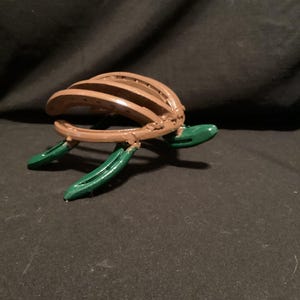 May include: A brown turtle sculpture made from horseshoes with green painted legs and head.