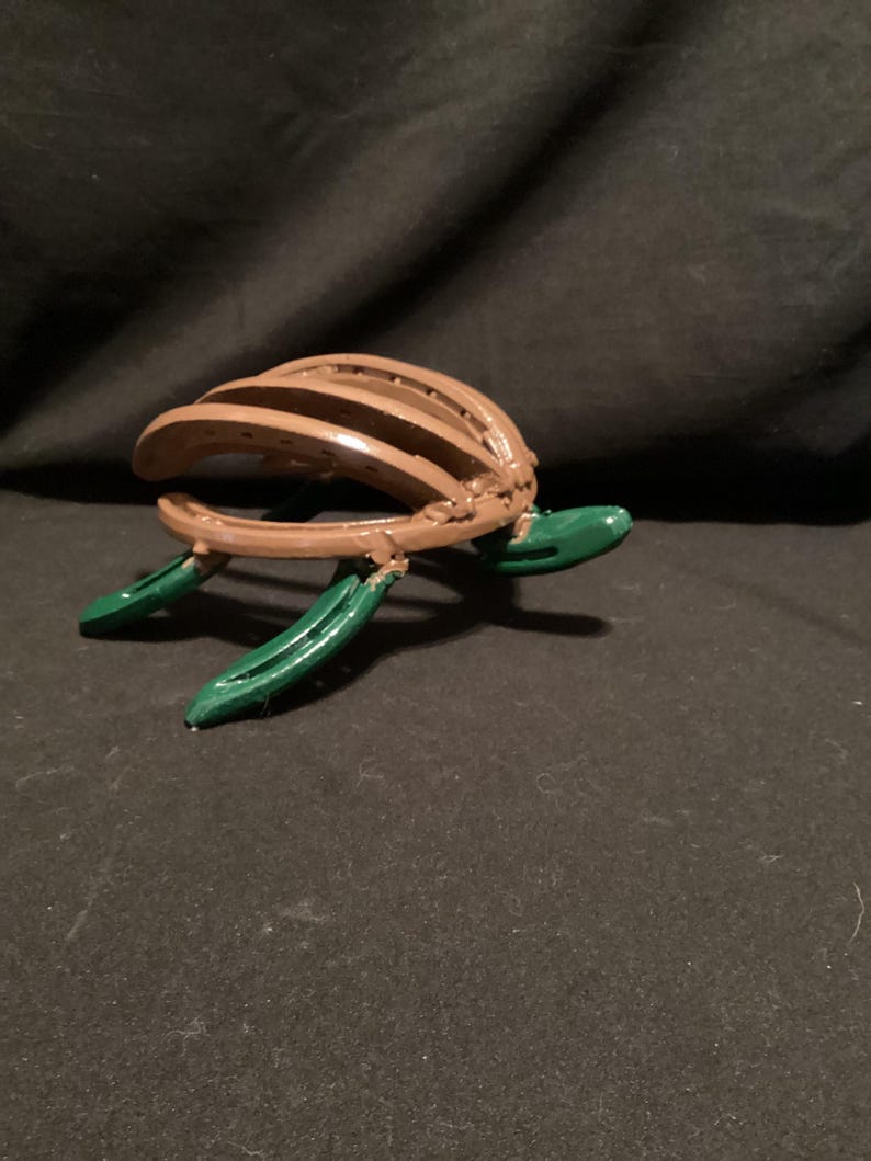 May include: A brown turtle sculpture made from horseshoes with green painted legs and head.