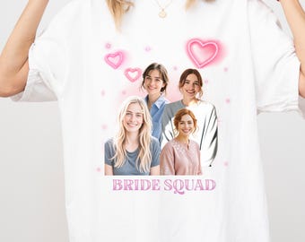 Könnte beinhalten: Weißes T-Shirt mit einem Gruppenfoto von vier Frauen, rosa Herzgrafiken und dem Text "BRIDE SQUAD". Das Design hat eine weiche, romantische Ausstrahlung. Die Frauen lächeln.