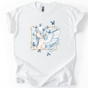 May include: White t-shirt featuring a detailed illustration of a woman with long white hair, angel wings, and blue butterflies. The artwork is framed in a gold border. The design is centered on the shirt.