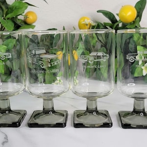 May include: Set of six clear glass wine glasses with gray square bases. Each glass features a different vintage car etched into the side. The cars include a 1969 Camaro, a 1968 Chevy Chevelle, a 1967 Monte Carlo, a 1967 Chevy II, a 1967 Corvette, and a 1969 Camaro.