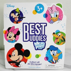 May include: A white box featuring Disney characters Goofy, Minnie Mouse, Mickey Mouse, Daisy Duck, Pluto, and Donald Duck. The box is labeled "Best Buddies Micro Popz!" and includes the text "Collect all 24 Micropopz!" and "Collectors album."