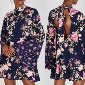 May include: A navy blue dress with a floral pattern in pink and yellow. The dress has long bell sleeves and a high neckline. The back of the dress has a keyhole opening. The dress is a mini length.