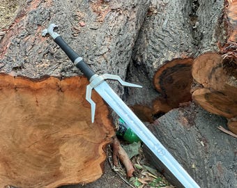May include: A silver and black sword with a stylized handle and a long, straight blade. The sword features a unique design with a crossguard and is set against a backdrop of a tree trunk.