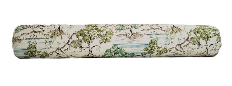 May include: A long, cylindrical cushion with a white background and a repeating pattern of green trees, brown mountains, and blue water. The cushion is ideal for adding a touch of nature to any room.