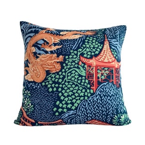 May include: A blue throw pillow with a red and orange dragon and pagoda design. The pillow features a repeating pattern of green leaves and blue and white waves.