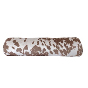 May include: A brown and white cowhide patterned bolster pillow.