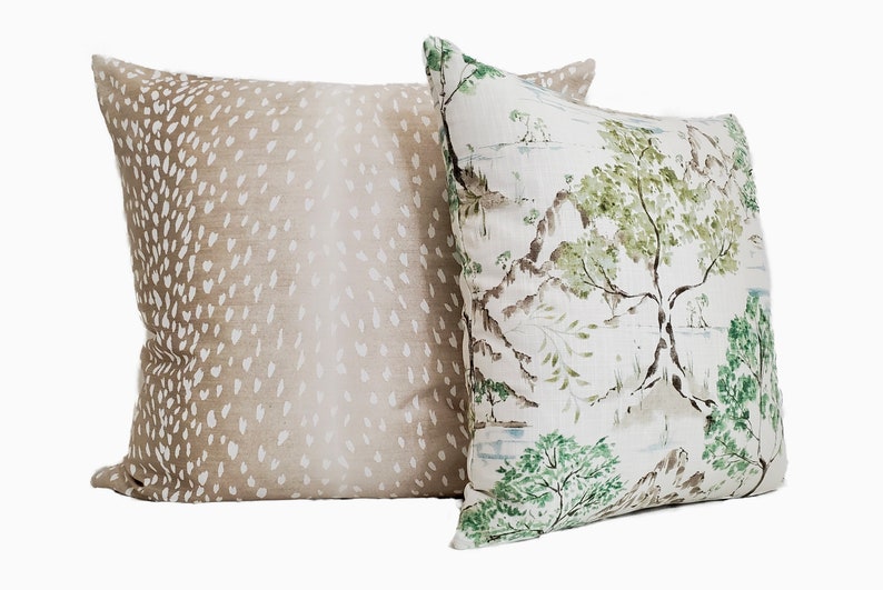 May include: Two decorative throw pillows, one with a brown and white deer print and the other with a green and white floral print.