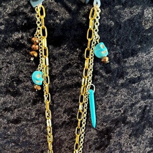 May include: A gold chain necklace with turquoise and brown beads. The necklace has multiple strands of chain and is layered.