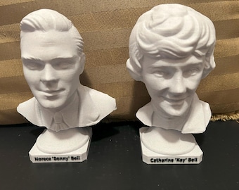 May include: Two white plaster busts of people on separate bases. The bust on the left is labeled "Horace 'Sonny' Bell". The bust on the right is labeled "Catherine 'Kay' Bell".