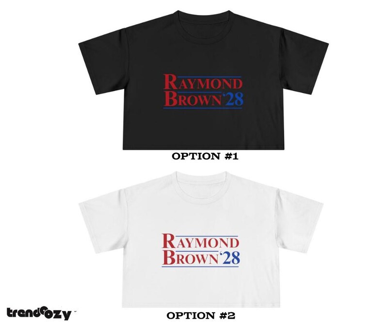 May include: Two t-shirts, one black and one white, each featuring the text "RAYMOND BROWN 28" in red and blue. The shirts are displayed with the option numbers #1 and #2 below them. The brand name "trendcozy" is in the bottom left corner.