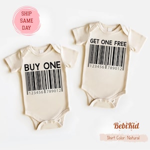 Puede incluir: Dos bodies de bebé beige con texto negro y diseños de código de barras. Uno dice "BUY ONE" y el otro "GET ONE FREE". Cada uno tiene el número de código de barras "123456789012". El logo de BebiKid y "Shirt Color: Natural" están abajo.