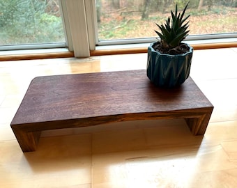 May include: A dark stained wooden plant stand with a rectangular top and a U-shaped base. A small teal-colored geometric pot with a succulent plant sits on the stand. The stand is approximately 18 inches long.